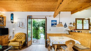 Un intérieur en bois comprenant un coin repas, un fauteuil en cuir et un téléviseur.
