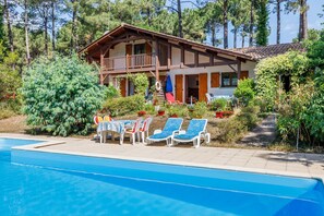 A two-story lodge with a balcony, a swimming pool, and lounge chairs. - Semi-Detached House 'Maison entre Lac et Océan' with Garden, Terrace & Wi-Fi (Biscarrosse)