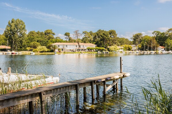A lakeside property with a dock extending into the water, surrounded by trees and a large house.