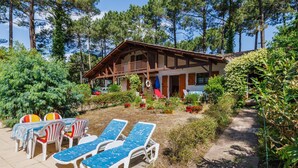 Un chalet doté d’une terrasse en bois, de chaises longues et d’un coin repas.