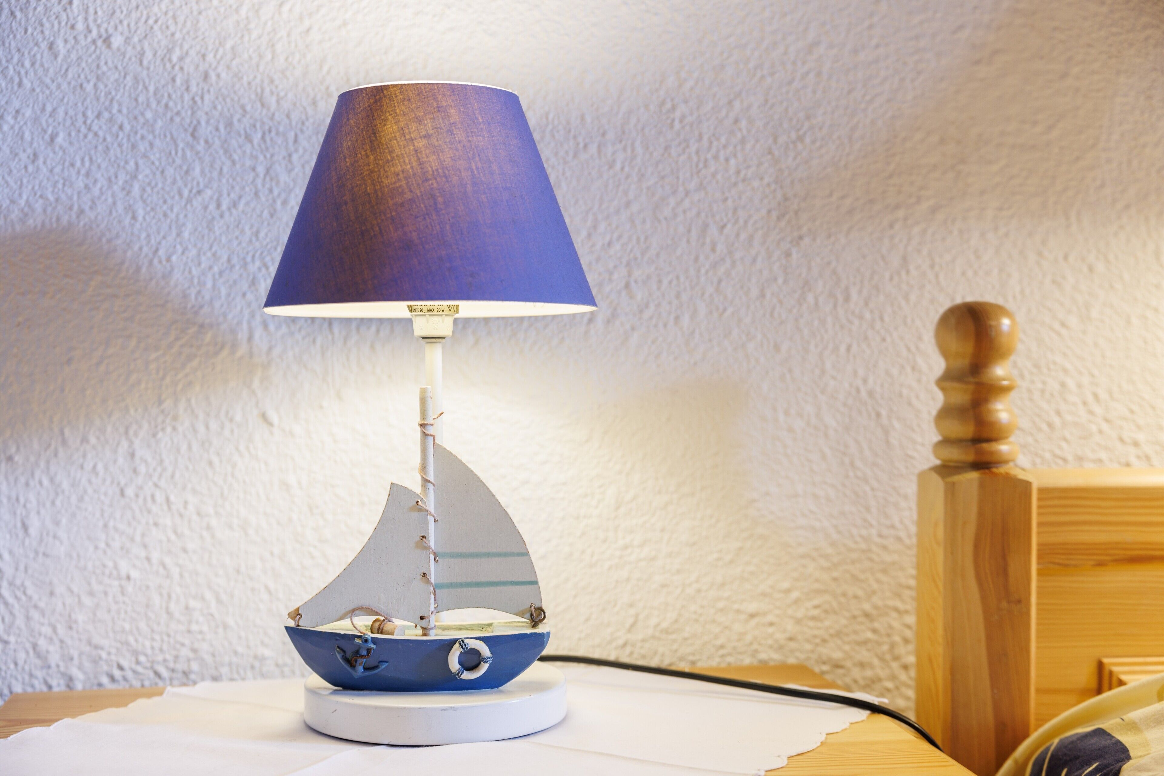 Une lampe décorée d’un motif de voilier, posée sur une table.