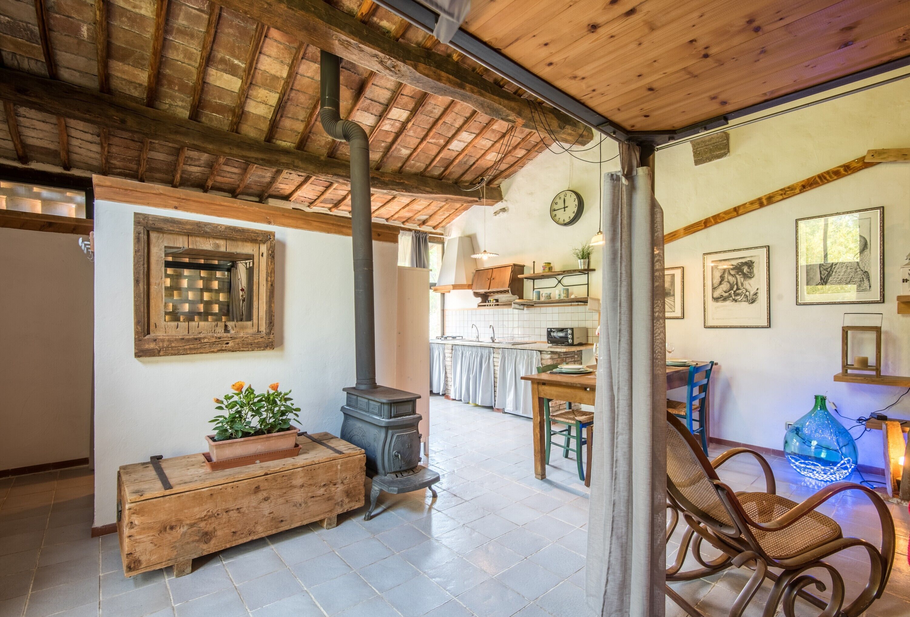 A rustic interior with a wooden bench, a stove, and a dining area with chairs.