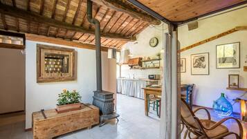 A rustic interior with a wooden bench, a stove, and a dining area with chairs.