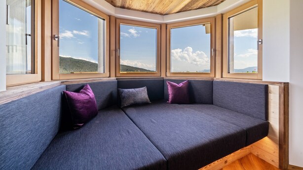 A corner seating area with a view of the outdoors through large windows. - Apartment 'Haughof - Blumenwiese' with Mountain View, Wi-Fi & Balcony, Very Quiet Location (Vöran bei Meran)