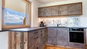 A modern kitchen with wooden cabinetry, a built-in oven, and a window with a view of the sky. - Apartment 'Haughof - Blumenwiese' with Mountain View, Wi-Fi & Balcony, Very Quiet Location (Vöran bei Meran)