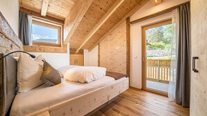 Un dormitorio con techo de madera, una cama con almohadas, una ventana y una puerta corredera a un balcón.