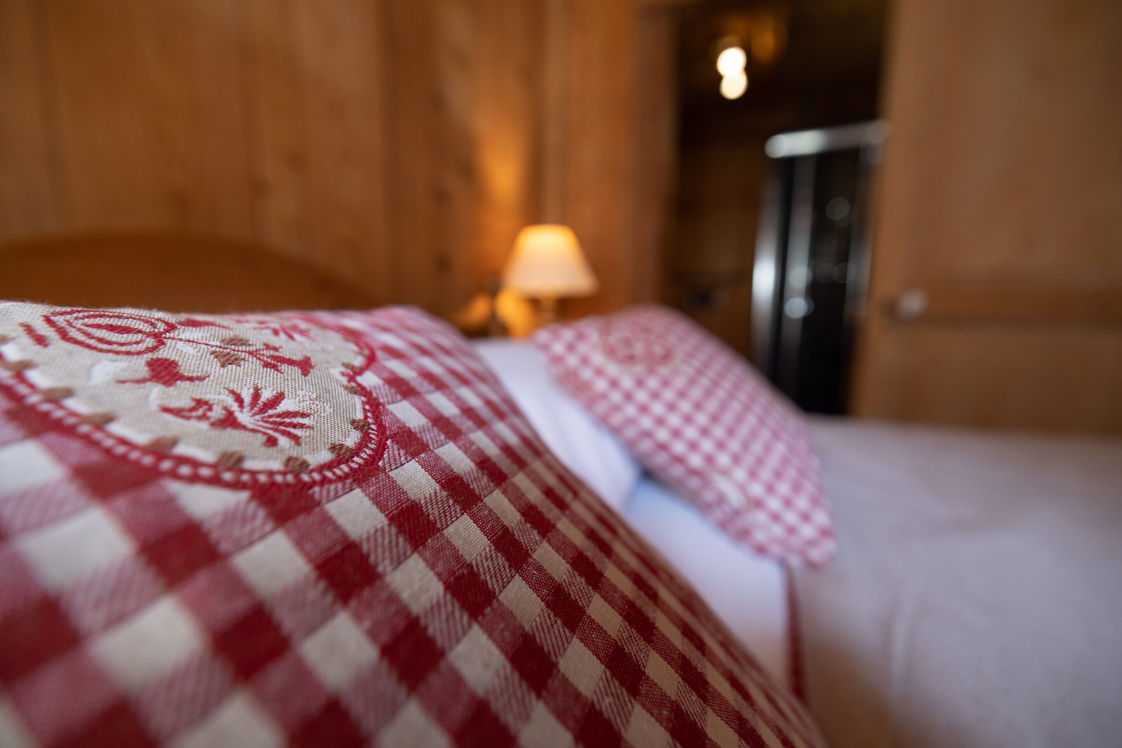 Een bed met een geruite deken en kussens.