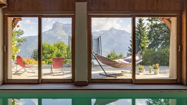 A room with large windows, a hammock, and outdoor seating.