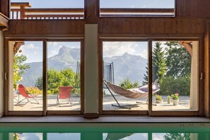 A room with large windows, a hammock, and outdoor seating. - Apartment "Ferme de Faustine 1 - Pool" with Mountain Views, Shared Pool, and Wi-Fi (Saint-Gervais-les-Bains)
