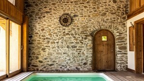 A stone wall, wooden door, and a swimming pool.