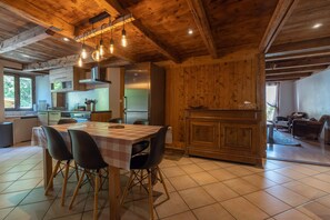 A kitchen with wooden cabinets, a dining table with chairs, and a refrigerator.