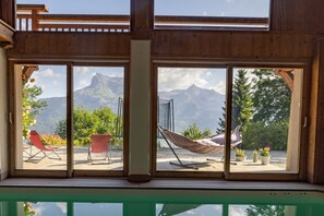 A room with large windows, a hammock, and two red chairs. - Apartment 'Ferme de Faustine 2' with Mountain View, Shared Pool and Wi-Fi (Saint-Gervais-les-Bains)