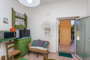 A room with a green cabinet, wicker sofa, and a microwave on a shelf. - Holiday Home 'Casa Maria' Near the Beach and Pet-Friendly (orosei)