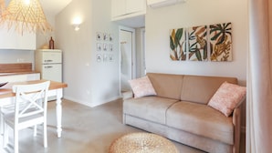 A modern living room with a sofa, a dining table, and a kitchen area. - La casa di Debora with A/C & Wi-Fi – Modern Apartment near La Cinta Beach (San teodoro)