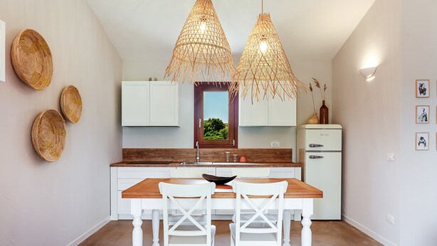 A modern kitchen with a wooden table, white chairs, and two hanging wicker lamps. - La casa di Debora with A/C & Wi-Fi – Modern Apartment near La Cinta Beach (San teodoro)