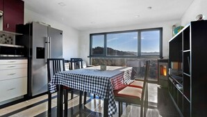A modern kitchen with a dining area, large windows, and a view of the outdoors.