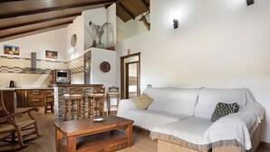 Una sala acogedora con una mesa de comedor de madera, un sofá y una cocina al fondo.