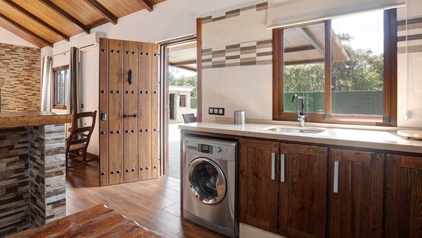 Una cocina moderna con lavadora incorporada, armarios de madera y un ventanal grande.