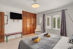 A bedroom with a bed, a bench, a television, and a wardrobe.