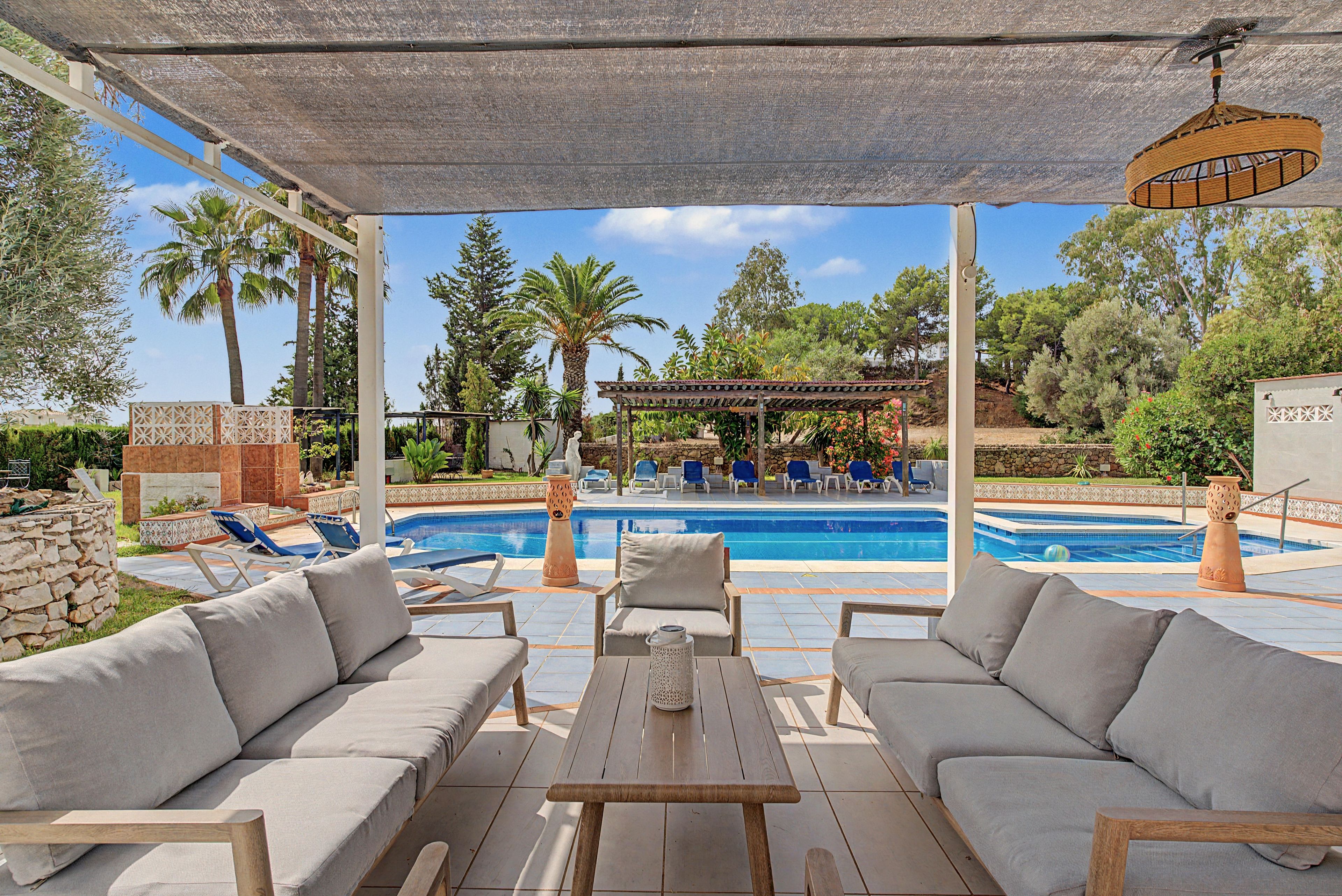 Un espace extérieur abrité comprenant une piscine, des chaises longues et une pergola.
