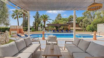 Un espace extérieur abrité comprenant une piscine, des chaises longues et une pergola.