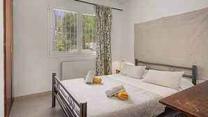 A bedroom with a bed, a window with curtains, a radiator, and a wooden door. - Casa Harriet with Pool, Terrace and WiFi (Mijas Pueblo)