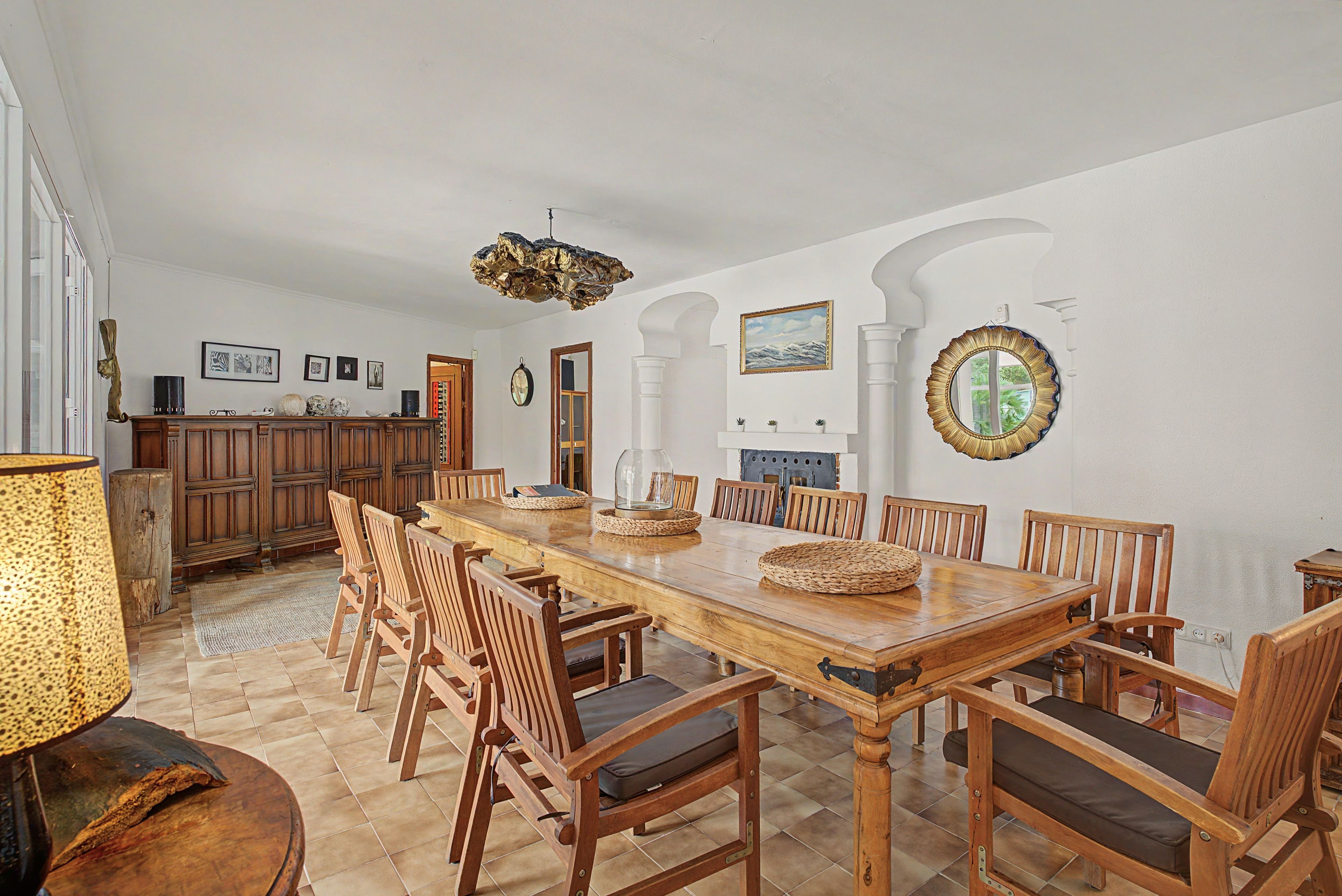 A spacious dining area with a long wooden table, multiple chairs, and a central island with a built-in stove.