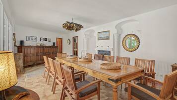 A spacious dining area with a long wooden table, multiple chairs, and a central island with a built-in stove.