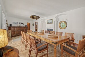 A spacious dining area with a long wooden table, multiple chairs, and a central island with a built-in stove.