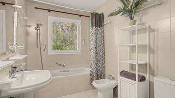 Une salle de bain équipée d’une baignoire, d’un bidet, de toilettes, d’un lavabo et d’une douche.