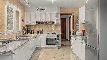 A modern kitchen with white cabinetry, a built-in oven, and a stainless steel refrigerator.