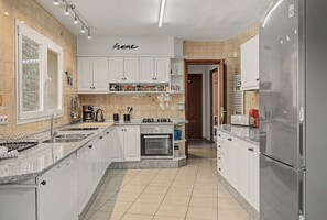A modern kitchen with white cabinetry, a built-in oven, and a stainless steel refrigerator.