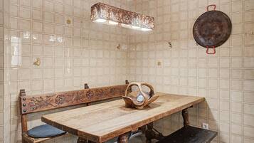 Un espace repas comprenant une table en bois, un banc et une chaise en bois originale, dotée d’un dossier incurvé.