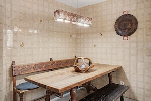 Un comedor con una mesa de madera, un banco y una silla de madera única con respaldo curvo.