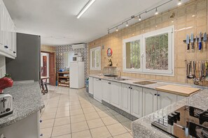 Ett modernt kök med vita skåp, en bänkskiva i granit och ett fönster med utsikt över grönområden.