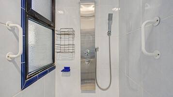 A bathroom with a shower, a towel rack, and a window with a blue frame.