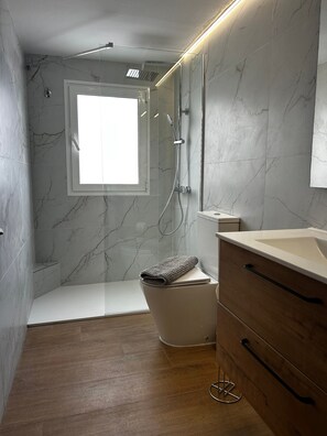 A modern bathroom with a shower, toilet, and vanity.