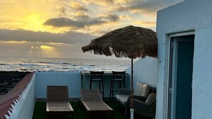 A rooftop terrace with a view of the ocean, a thatched umbrella, and outdoor furniture. - Apartment 'El Cotillo Mar Beach' with Sea View, Terrace & Wi-Fi (El Cotillo)