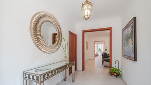 A hallway with a round mirror, a glass console table, a hanging light fixture, and a framed painting on the wall. - Holiday Home Casa en Sineu with Mountain View, Terrace & Wi-Fi (Sineu)