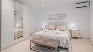A modern bedroom with a large bed, bedside tables, a bench, and a wardrobe. - Holiday Home Casa en Sineu with Mountain View, Terrace & Wi-Fi (Sineu)