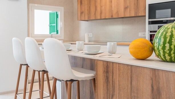 A modern kitchen with wooden cabinets, a white countertop, and bar stools. - Holiday Home Casa en Sineu with Mountain View, Terrace & Wi-Fi (Sineu)