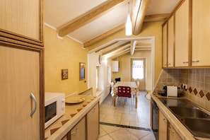 A kitchen with wooden cabinets, a microwave, a sink, and a dining area with a table and chairs.