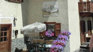 A building with a balcony, a table with chairs, and a flower arrangement. - Appartamento Giada with Mountain View, Balconies & Wi-Fi (Livigno)