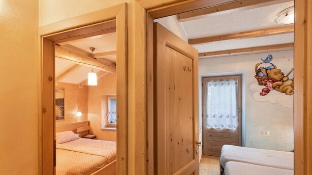 A wooden-framed room with a bed, a small desk, and a wall with a bear illustration. - Appartamento Giada with Mountain View, Balconies & Wi-Fi (Livigno)