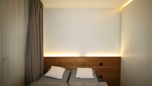 A hotel room with two beds, a wooden headboard, and a wall-mounted light fixture. - Vacation apartment SeeFugium (Tegernsee)