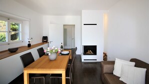 A modern dining area with a wooden table, chairs, and a vase of flowers. - Vacation apartment SeeFugium (Tegernsee)