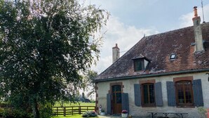 A two-story house with a tiled roof, a wooden fence, and a well-maintained lawn. - Farmhouse with pool, pets allowed in Sologne Bourbonnaise (Mercy)
