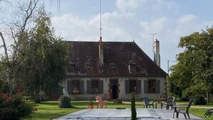 A building with a symmetrical facade, a central entrance, and a paved courtyard with outdoor furniture. - Farmhouse with pool, pets allowed in Sologne Bourbonnaise (Mercy)