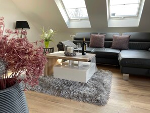 A modern living room with a sofa, a coffee table, a lamp, and a skylight.