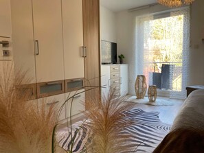 A bedroom with a bed, a wardrobe, a television, a window with a view, and decorative vases.